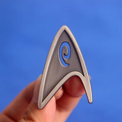 ST-Star X Trek enamel lapel pin held in hand against a blue background, perfect for backpacks and fashion accessories.